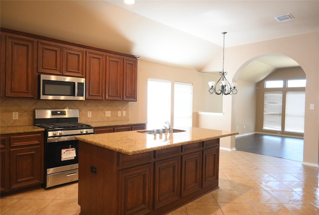 kitchen with arched walkways, a sink, stainless steel appliances, vaulted ceiling, and tasteful backsplash