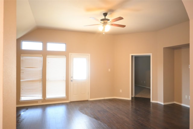 empty room featuring lofted ceiling, dark wood-style floors, a ceiling fan, and baseboards