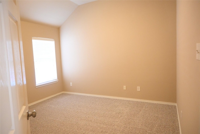 carpeted spare room featuring lofted ceiling and baseboards