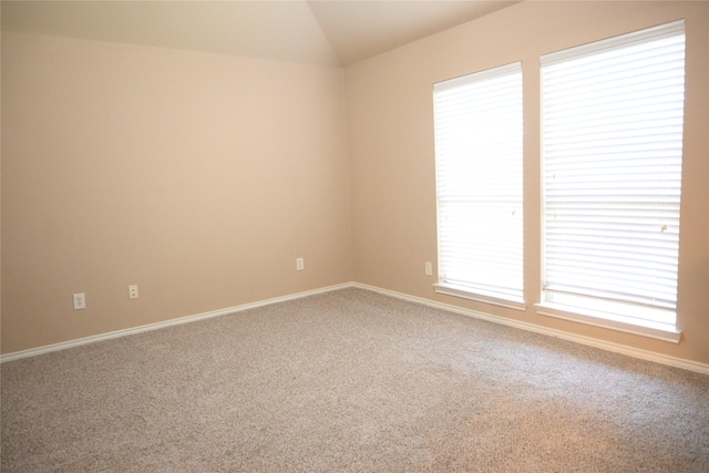 unfurnished room featuring carpet flooring, baseboards, and lofted ceiling