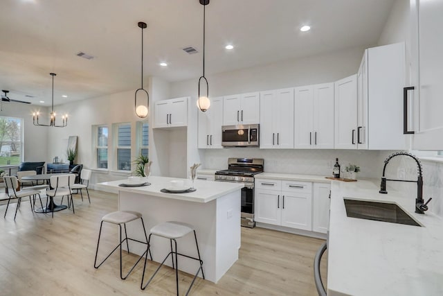 kitchen with visible vents, decorative backsplash, light wood-style flooring, appliances with stainless steel finishes, and a sink