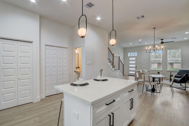 kitchen with open floor plan, white cabinets, visible vents, and light wood finished floors