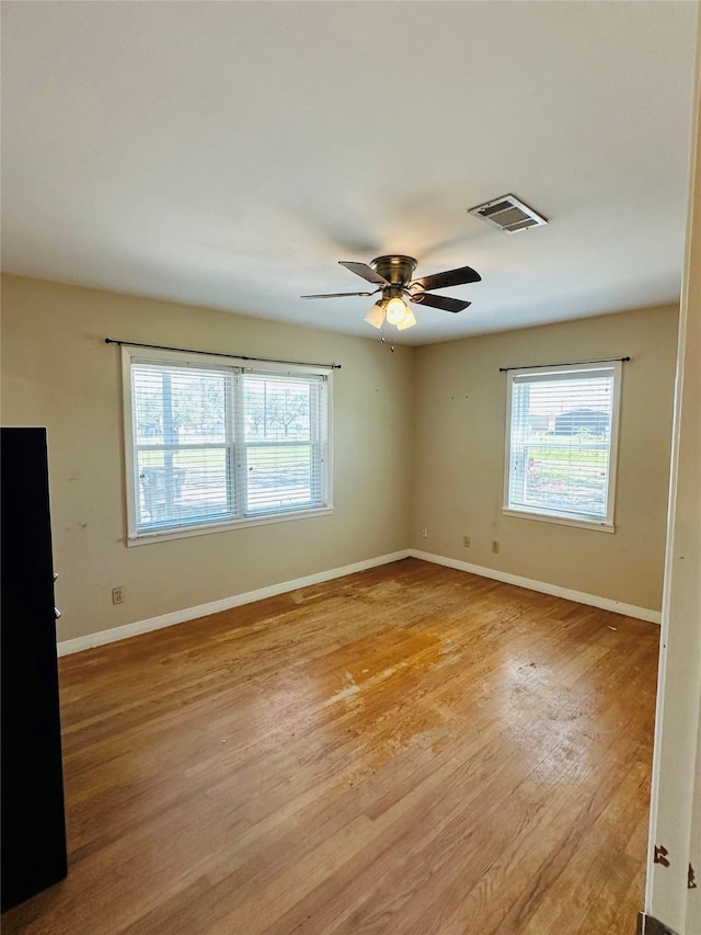 empty room featuring visible vents, a healthy amount of sunlight, baseboards, and light wood-style floors