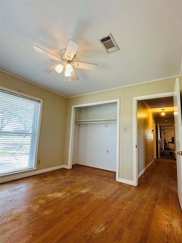 unfurnished bedroom with visible vents, a ceiling fan, wood finished floors, a closet, and baseboards