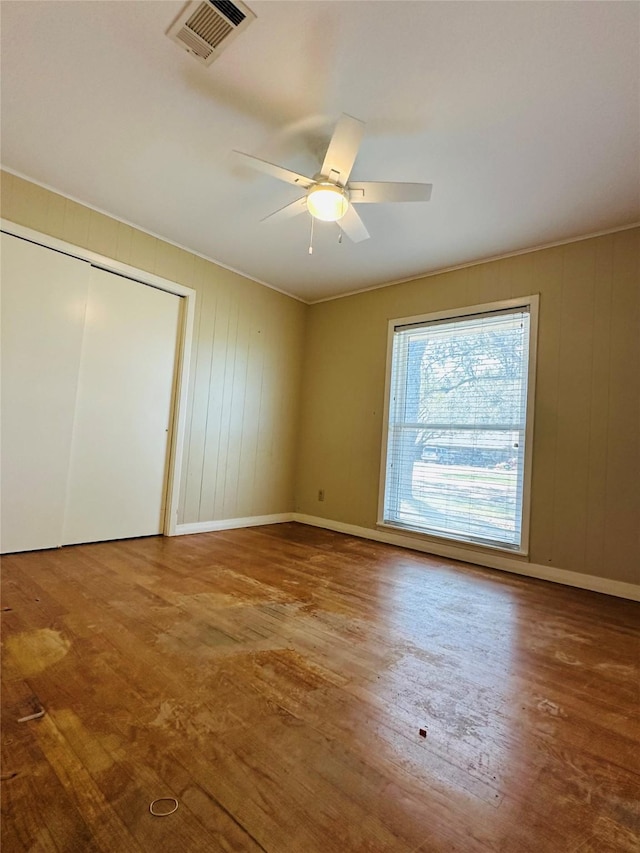 unfurnished bedroom featuring wood finished floors, visible vents, a closet, and baseboards