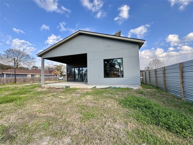 rear view of house featuring a yard and fence