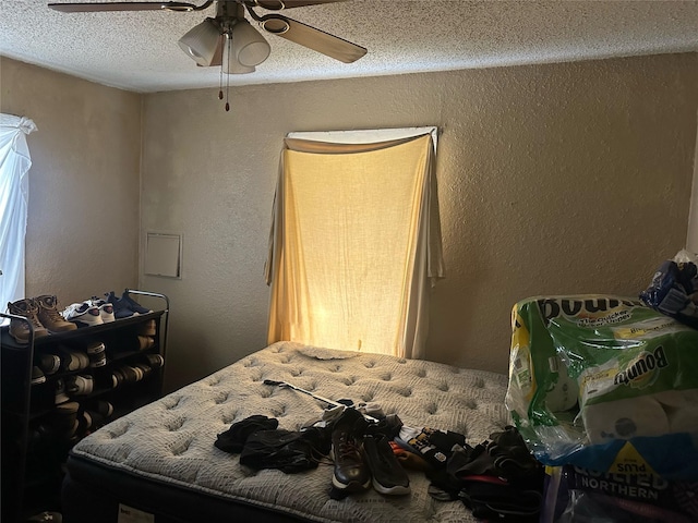 bedroom featuring a textured ceiling, ceiling fan, and a textured wall