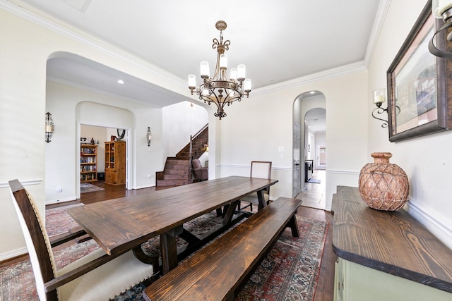 dining area featuring crown molding, arched walkways, stairs, and a chandelier