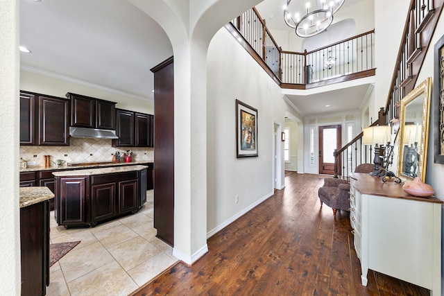 entryway featuring crown molding, arched walkways, an inviting chandelier, and stairway