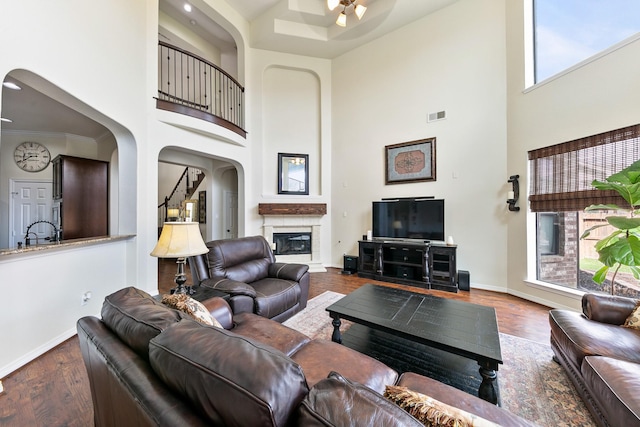 living room with arched walkways, a high ceiling, ceiling fan, and visible vents