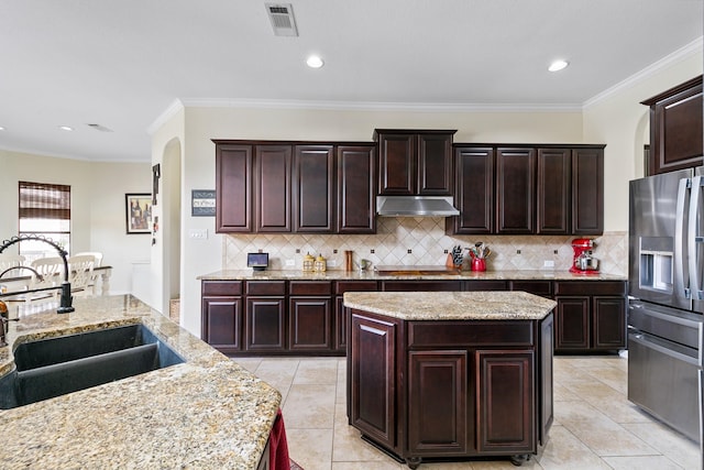 kitchen with a sink, stainless steel fridge with ice dispenser, arched walkways, under cabinet range hood, and visible vents