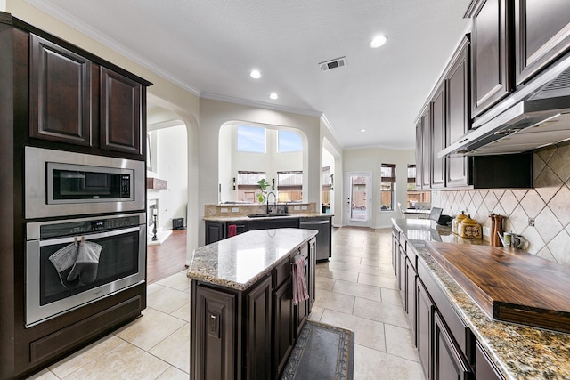 kitchen featuring appliances with stainless steel finishes, ornamental molding, a wealth of natural light, and visible vents