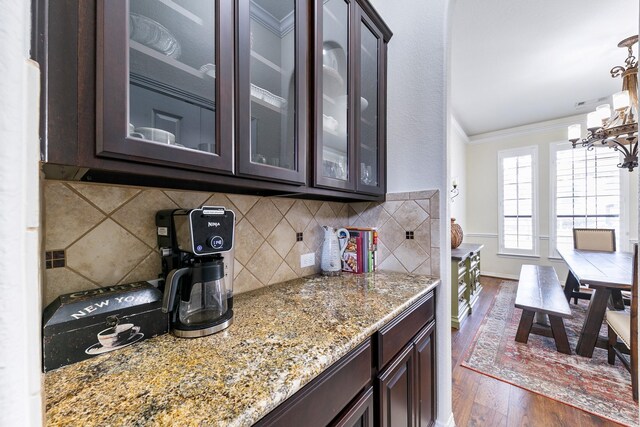 kitchen with an inviting chandelier, ornamental molding, dark wood-style flooring, and dark brown cabinets