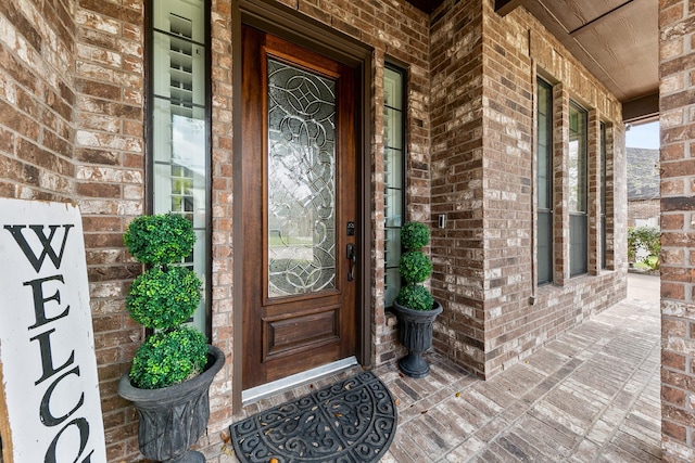 view of exterior entry with covered porch and brick siding