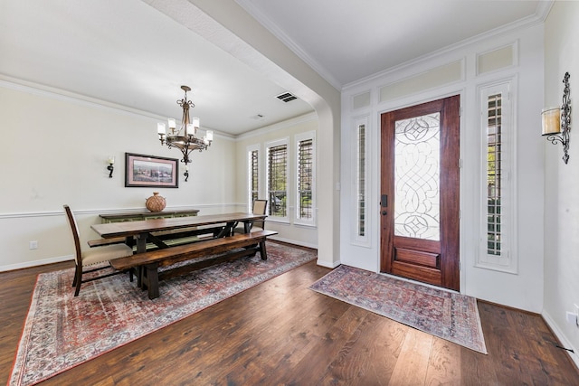 foyer featuring crown molding, visible vents, dark wood-style flooring, baseboards, and a chandelier