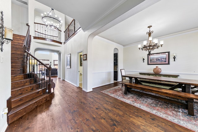 dining space with arched walkways, wood finished floors, a chandelier, and stairway