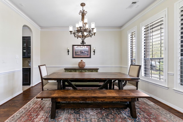 dining area with crown molding, wood finished floors, a chandelier, and visible vents