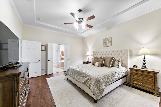 bedroom featuring a ceiling fan, dark wood-style flooring, a raised ceiling, ornamental molding, and ensuite bath
