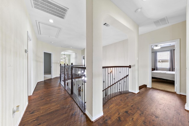 hallway featuring wood-type flooring, visible vents, and attic access