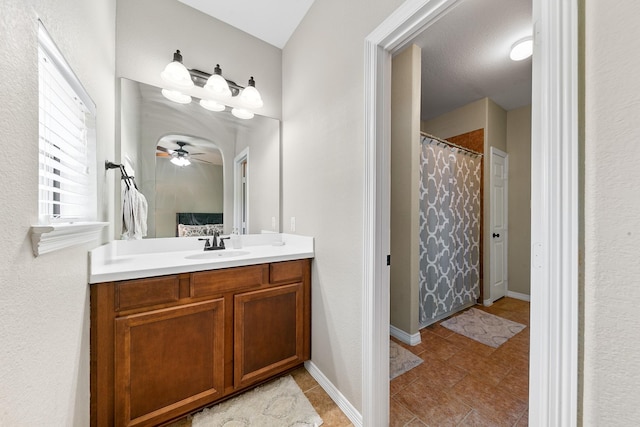 ensuite bathroom with a ceiling fan, curtained shower, vanity, baseboards, and ensuite bathroom