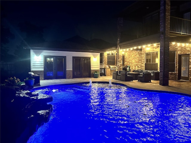 pool at night featuring an outdoor living space, french doors, an outdoor pool, and a patio area