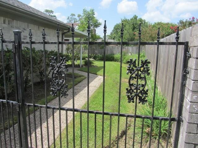 view of gate with a lawn and fence