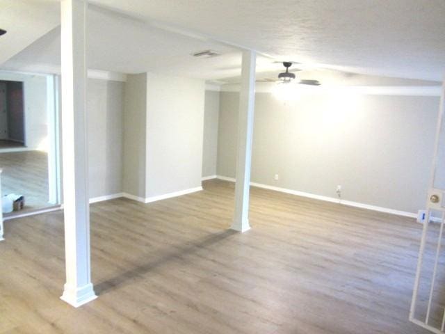 below grade area featuring wood finished floors, a ceiling fan, and baseboards