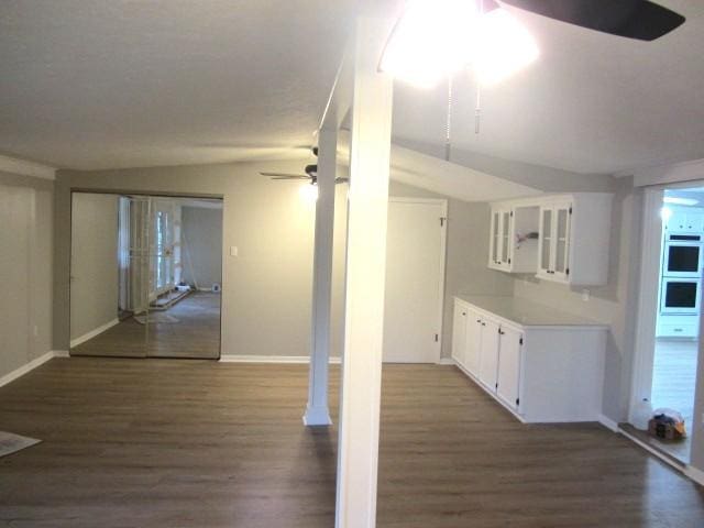 interior space with wood finished floors, a ceiling fan, and baseboards