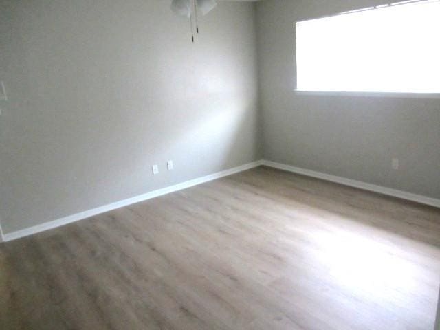 empty room featuring ceiling fan, baseboards, and wood finished floors