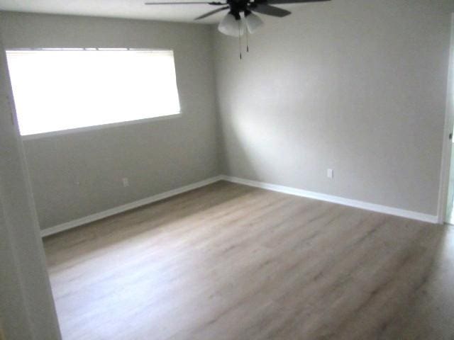 spare room with baseboards, wood finished floors, and ceiling fan