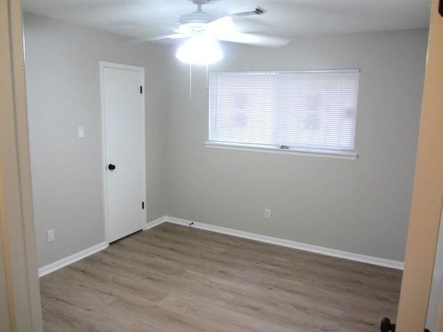 unfurnished room with wood finished floors, a ceiling fan, baseboards, and visible vents