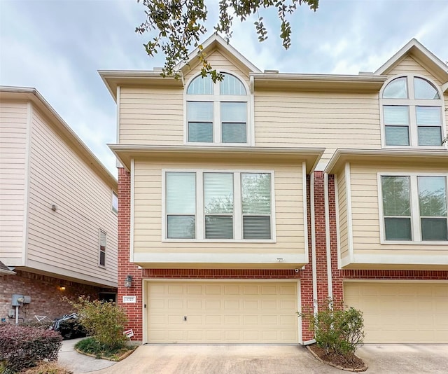 view of property featuring a garage, brick siding, and driveway