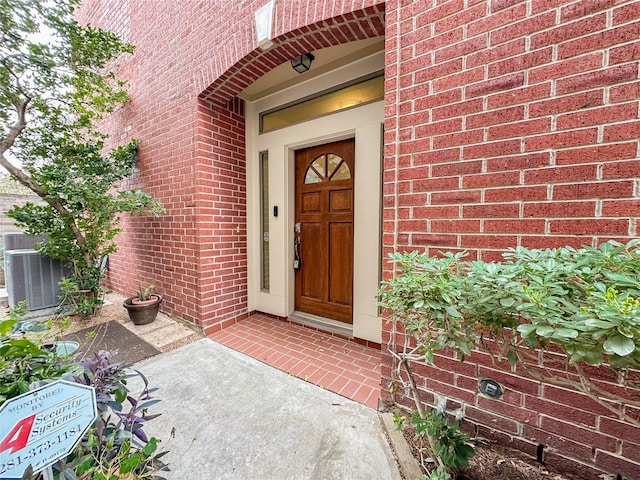 property entrance with cooling unit and brick siding