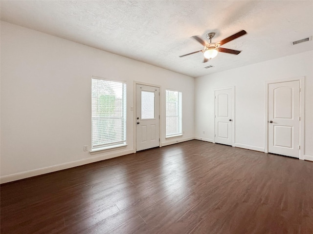 foyer entrance featuring visible vents, dark wood-type flooring, baseboards, a textured ceiling, and a ceiling fan