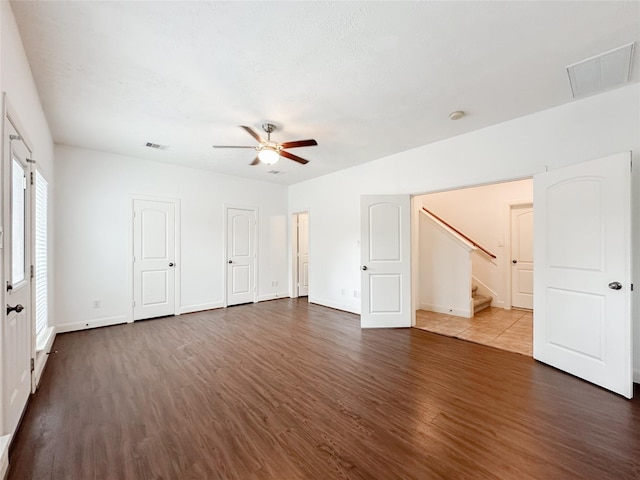 unfurnished bedroom featuring visible vents, baseboards, two closets, and dark wood-style flooring