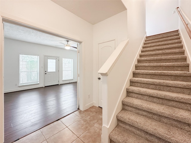 interior space with light tile patterned floors, stairway, baseboards, and a ceiling fan