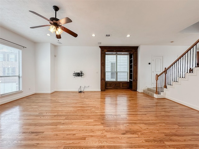 unfurnished living room with a ceiling fan, baseboards, recessed lighting, stairs, and light wood-type flooring