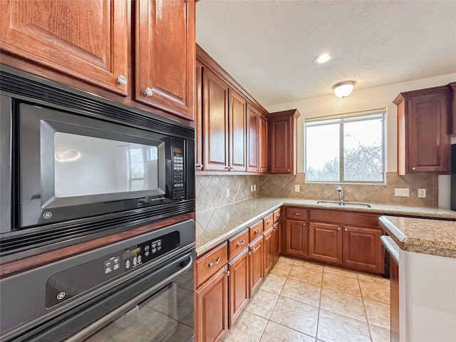 kitchen featuring tasteful backsplash, oven, black microwave, light countertops, and a sink