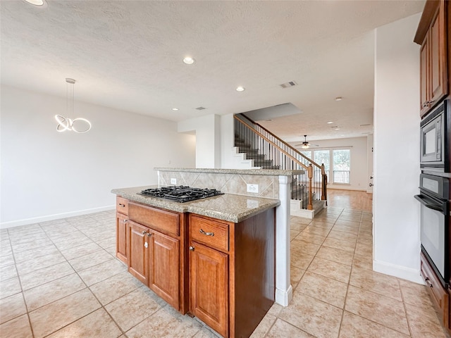 kitchen featuring visible vents, black appliances, light stone counters, open floor plan, and brown cabinetry