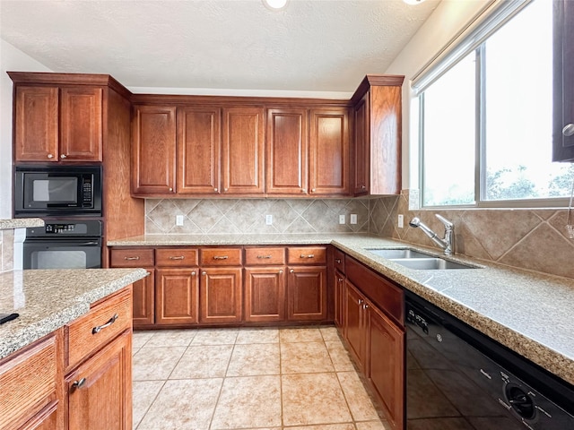 kitchen with light tile patterned floors, decorative backsplash, brown cabinets, black appliances, and a sink