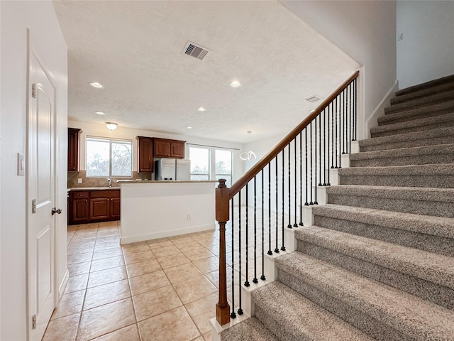 staircase with tile patterned floors, recessed lighting, visible vents, and a textured ceiling