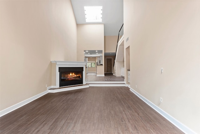 148 Sugarberry Cir, Houston, TX 77024 - unfurnished living room featuring a lit fireplace, visible vents, a towering ceiling, wood finished floors, and baseboards