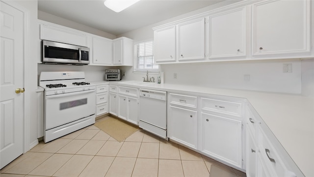 kitchen with light countertops, light tile patterned floors, white cabinets, white appliances, and a sink