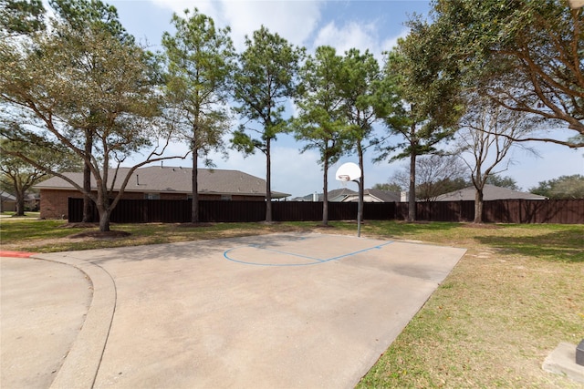 exterior space featuring community basketball court, fence, and a lawn