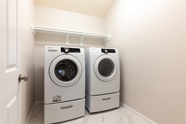 washroom featuring washer and dryer, laundry area, baseboards, and marble finish floor