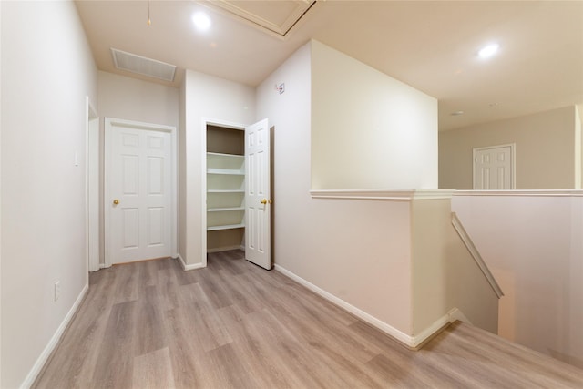 hallway with visible vents, baseboards, an upstairs landing, recessed lighting, and wood finished floors