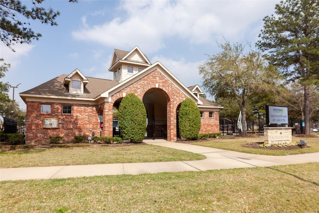 traditional home with brick siding, a shingled roof, a front yard, and fence