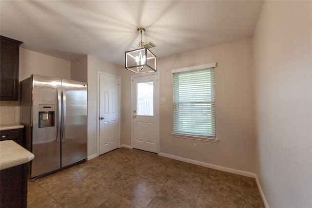 kitchen featuring baseboards, stainless steel fridge with ice dispenser, light countertops, dark brown cabinets, and decorative light fixtures