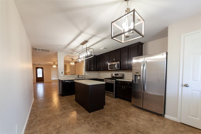 kitchen with a kitchen island, a sink, light countertops, appliances with stainless steel finishes, and ceiling fan with notable chandelier