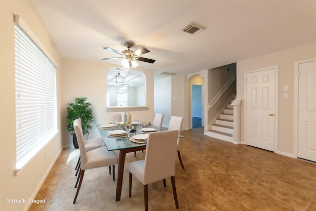 dining area with visible vents, a ceiling fan, arched walkways, baseboards, and stairs